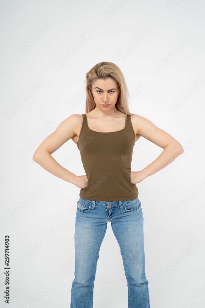 A young attractive girl is standing, hands on sides, looking indignantly at the camera. Isolated on white background A young attractive girl is standing, hands on sides, looking indignantly at the camera. Isolated on white background
