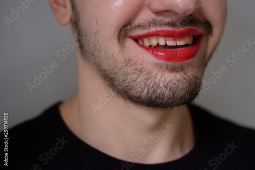 Man with a red lipstick on smiling. Lips and beard close-up. Lgbt comunity. Transsexual guy. Transgender.