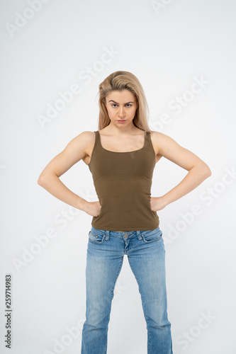 A young attractive girl is standing, hands on sides, looking indignantly at the camera. Isolated on white background
