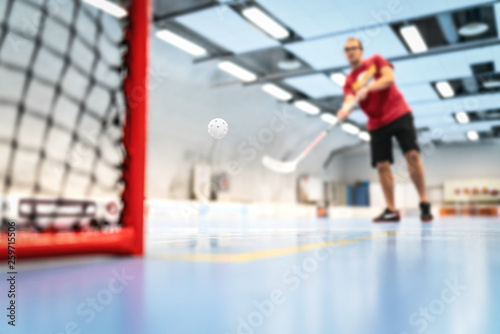 Floorball training on court. Man training floor hockey in arena. Slap shot on goal.
