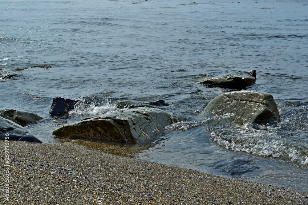 coast of the bay with rubble stones in the water