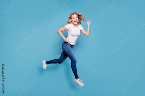Full length body size view portrait of nice lovely winsome attractive cheerful cheery optimistic wavy-haired lady in casual white t-shirt running fast isolated over blue background