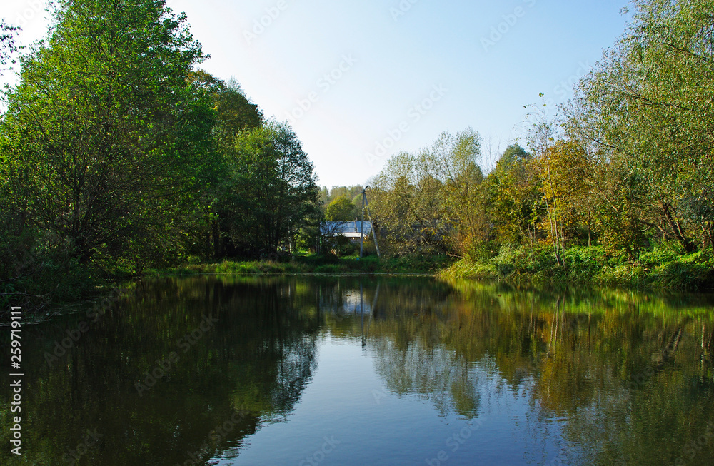 Rural landscape. Old house in the distance against the backdrop of the lake.