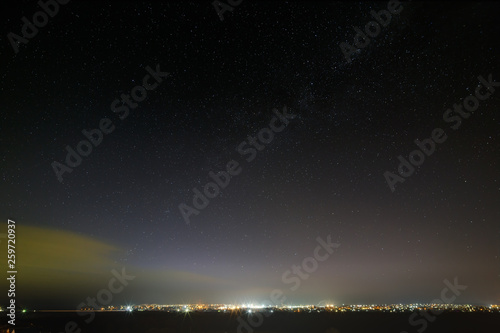 Bright stars in the night sky over the city. Light pollution from street lamps.