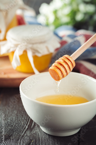 Honey background. Sweet honey in glass jar on wooden background. © NewFabrika