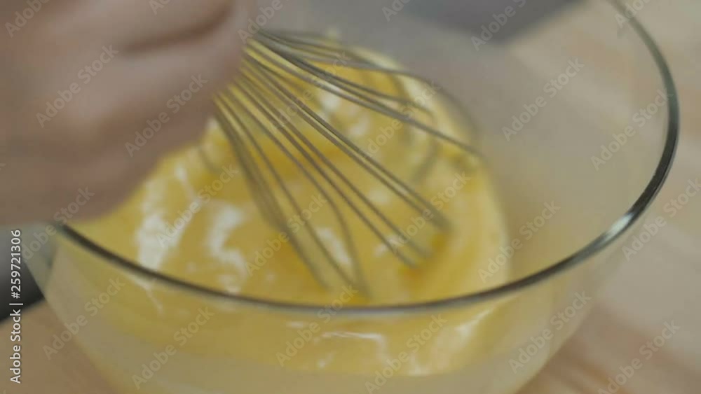 Girl whisking eggs. Whipped eggs in glass bowl Girl whisking eggs. Whipped eggs in glass bowl