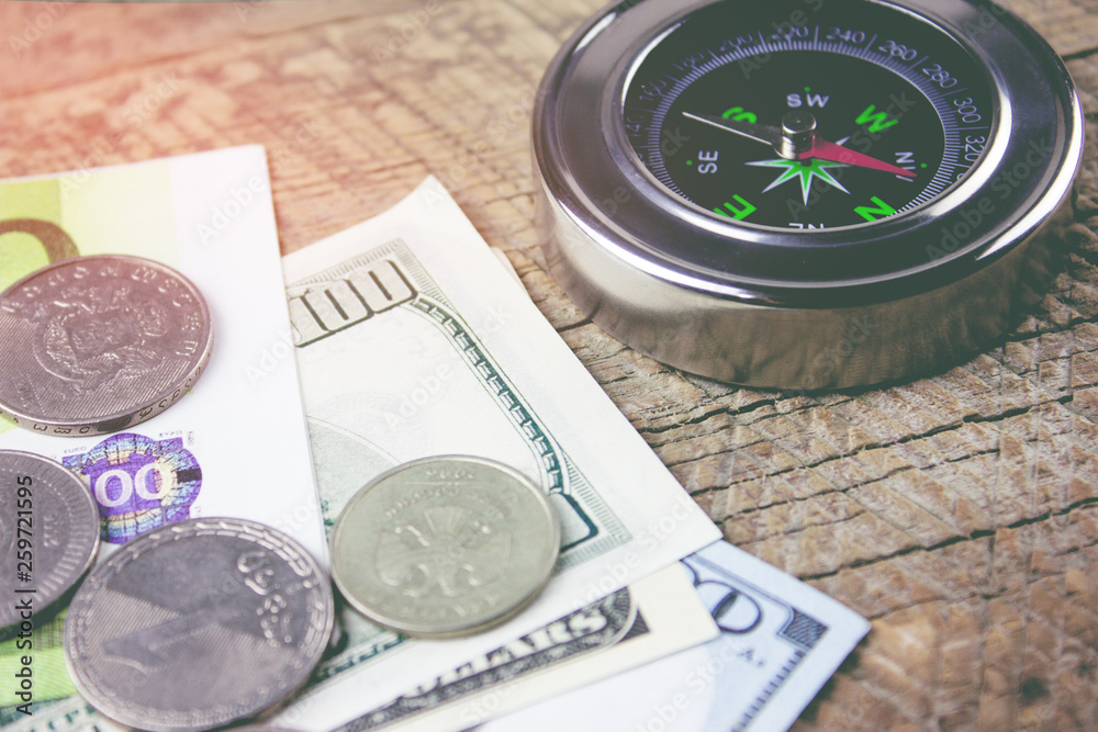 compass and money on a wooden table compass and money on a wooden table