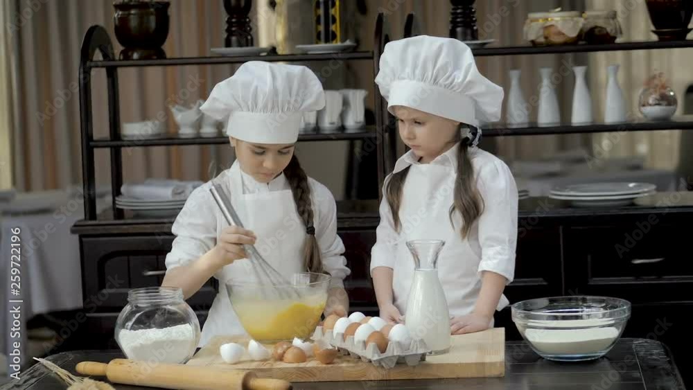 Young girl whipping eggs in glass bowl at wooden table Young girl whipping eggs in glass bowl at wooden table