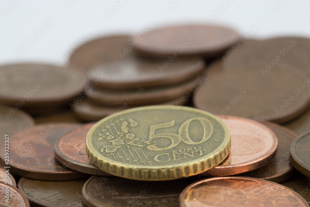 Coin of fifty euro cents on several bronze coins of five euro cents. White background. Coin of fifty euro cents on several bronze coins of five euro cents. White background.