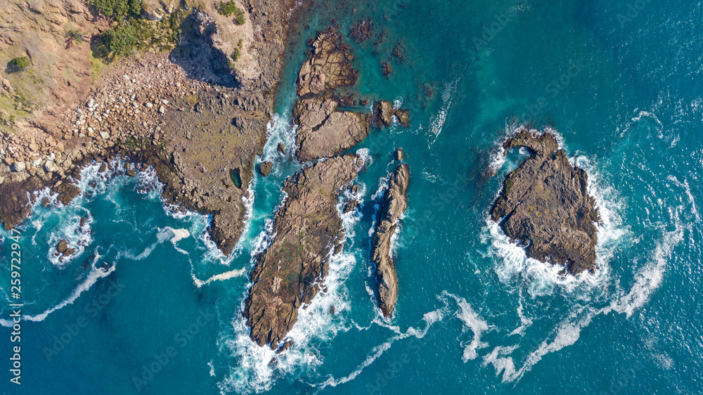 aerial shot of waves hitting rocks