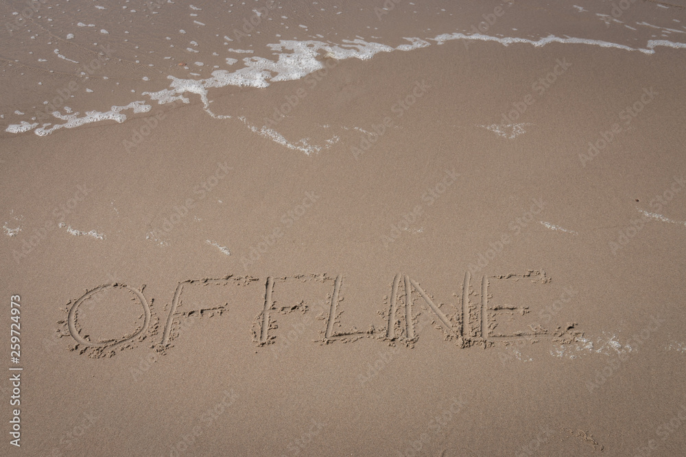Fototapeta premium The word “offline” written in the sand symbolizing a time-out