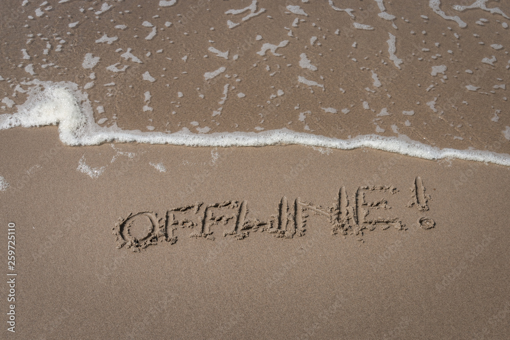 Fototapeta premium The word “offline” written in the sand symbolizing a time-out
