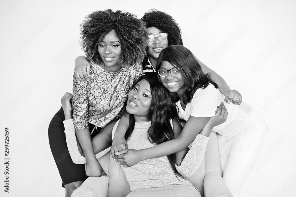 Happy brightful positive moments of four african girls. Having fun and smiling on chair against white empty wall. Lovely moments of four hugging best friends.