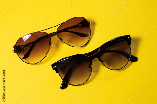 Sunglasses lie on a yellow background, close-up
