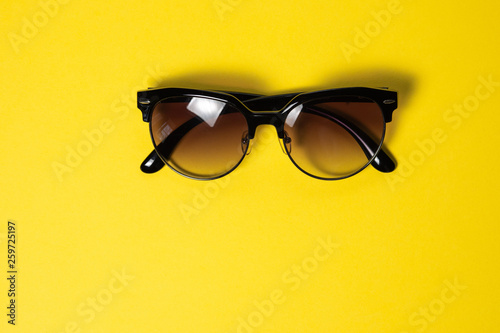 Sunglasses lie on a yellow background, close-up