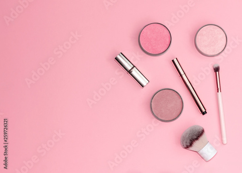 Flat lay composition with decorative makeup products on pastel pink background.