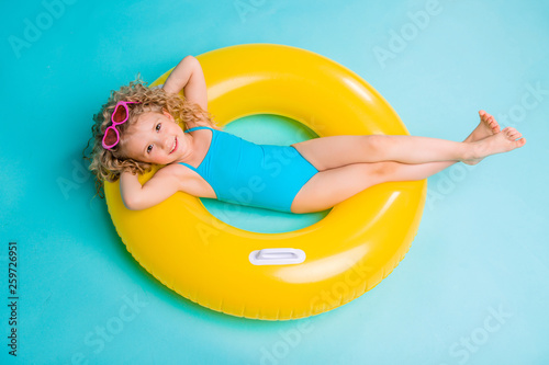Cute girl in swimsuit holding swimming circle. Isolated on blue background .Summer holidays - pretty girl with inflatable ring  © КРИСТИНА Игумнова