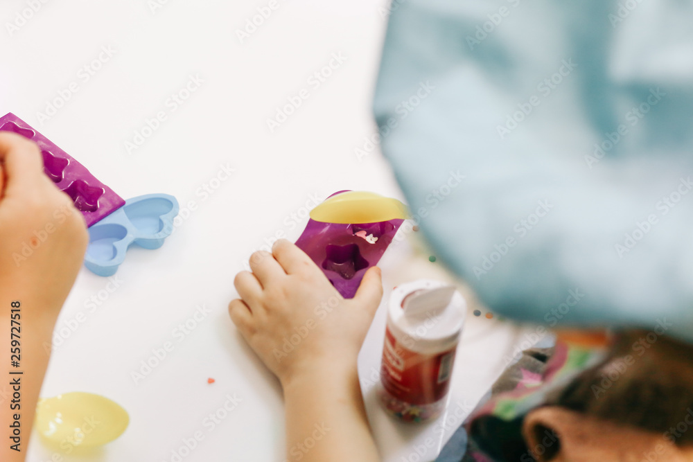 hands of a child, a master class in cooking chocolate, folding fruit and chocolate into molds hands of a child, a master class in cooking chocolate, folding fruit and chocolate into molds