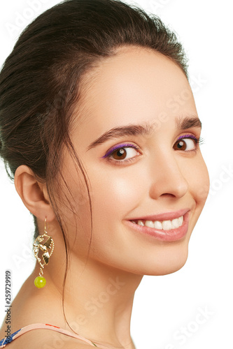 фотографія Closeup portrait of a smiling lady with lilac eyeshadows and dark brunette hair, wearing voguish long earrings