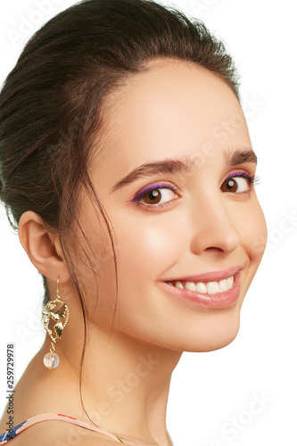 фотографія Closeup portrait of a smiling lady with lilac eyeshadows and tied back hair, wearing long dangle earrings