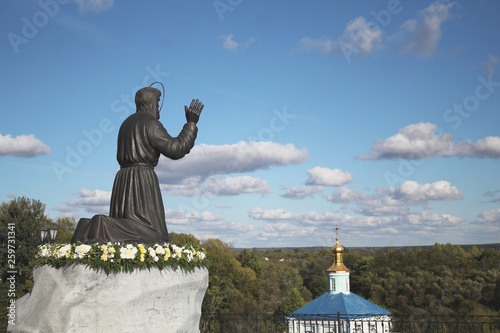 Monument to Seraphim Sorovsky against the background of the Church and the blue sky on a Sunny summer day photo