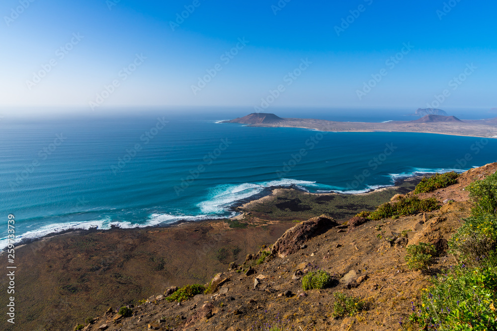Spain, Lanzarote, Coast of famara and island la graciosa behind blooming flowers at guinate viewpoint Spain, Lanzarote, Coast of famara and island la graciosa behind blooming flowers at guinate viewpoint