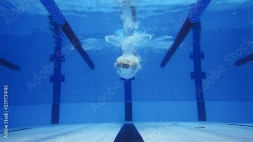 Muscular man under water in a swimming pool in super slow motion