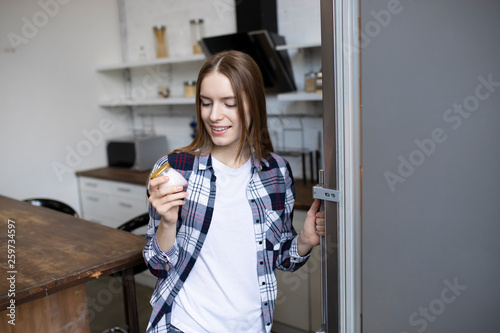 Beautiful girl takes yogurt from the fridge. Athletic woman on a diet