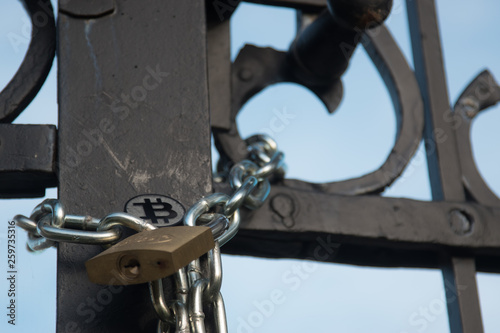 Bit coin on old gate with lock and chain