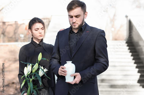 Couple with mortuary urn and flowers at funeral
