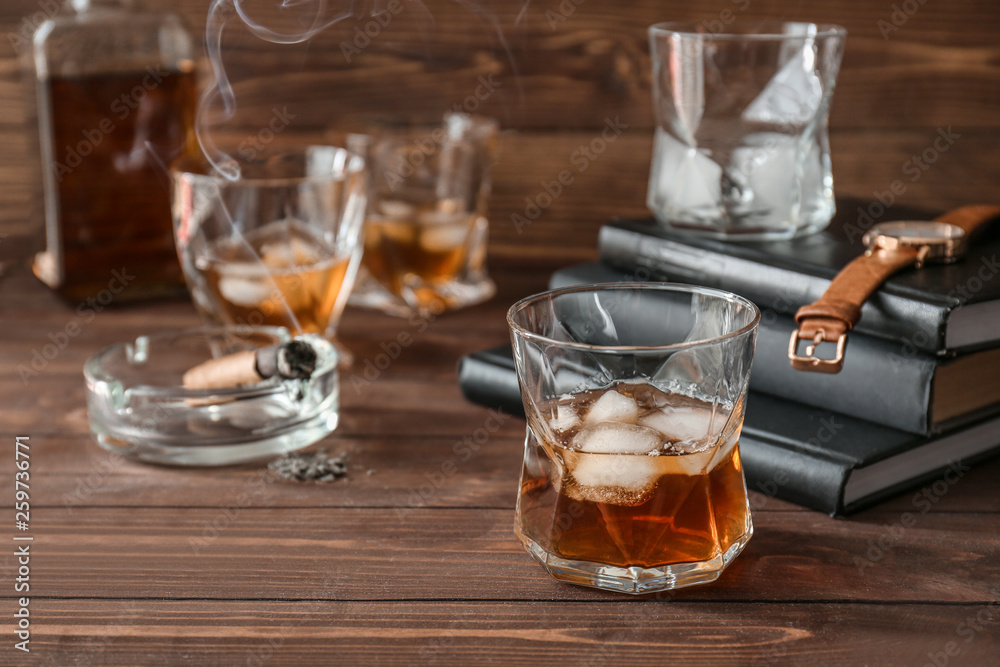 Glass of cold whiskey with cigar on wooden table Glass of cold whiskey with cigar on wooden table
