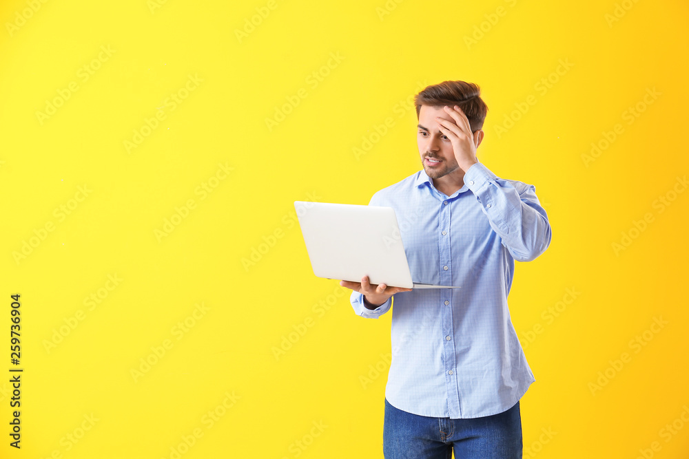 Shocked male programmer with laptop on color background Shocked male programmer with laptop on color background