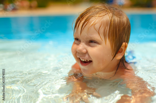 Smiling blond-haired toddler lying in the swimming pool