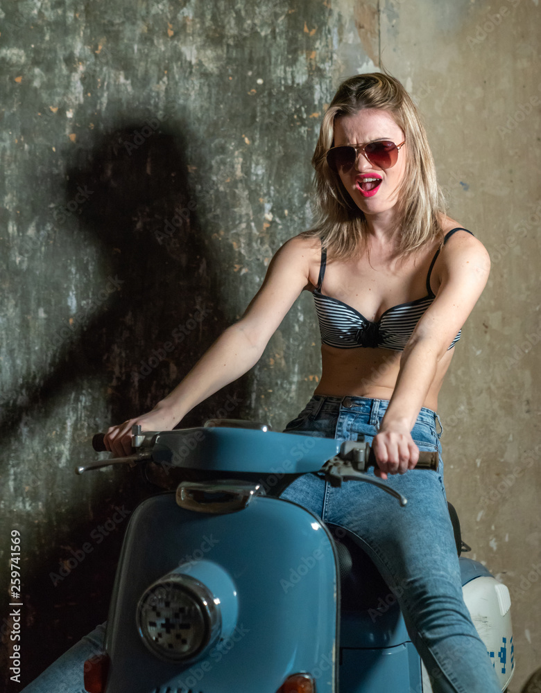 Beautiful young girl in a bodice and jeans in on a scooter