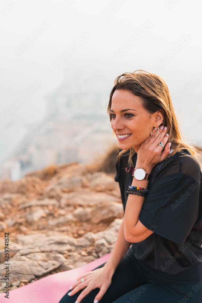 Beautiful young woman doing yoga at the top of the mountain with views from the city during a nice sunset. Freedom and yoga concept. Beautiful young woman doing yoga at the top of the mountain with views from the city during a nice sunset. Freedom and yoga concept.
