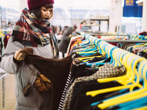 Photos Young woman is browsing a rail of clothes at mall store