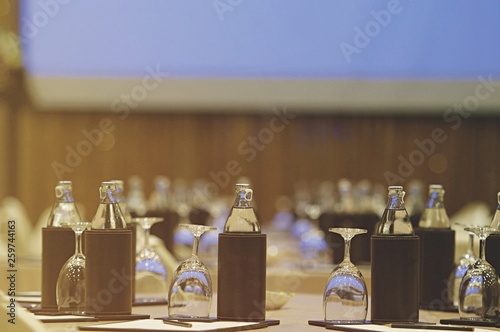 Image close up environmental of White paper with pencil and glass with bottled water setup on the table for the speech of the lecture ,Prepare conference in the hotel. Processed color tone.