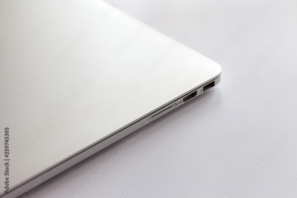 Closed metal laptop on a white table. Visible USB ports, HDMI and card reader