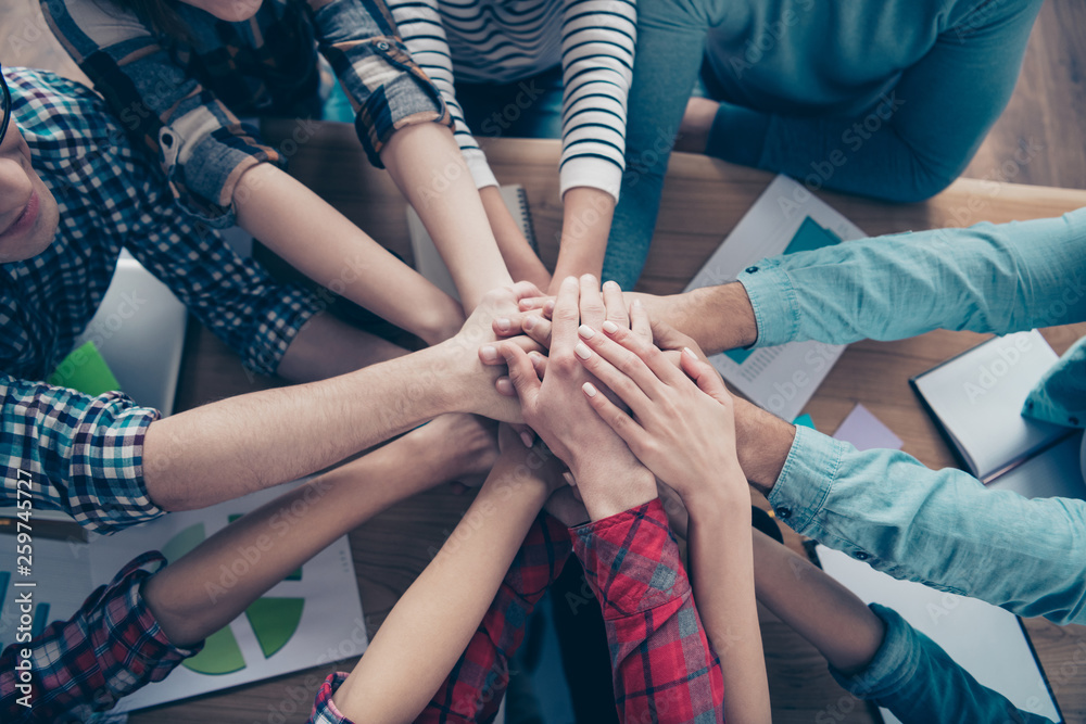 Cropped top above high angle view of company executive staff wearing casual putting palms together motivation over table desk at workplace workstation indoors