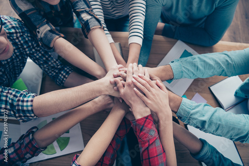 Cropped top above high angle view of company executive staff wearing casual putting palms together motivation over table desk at workplace workstation indoors