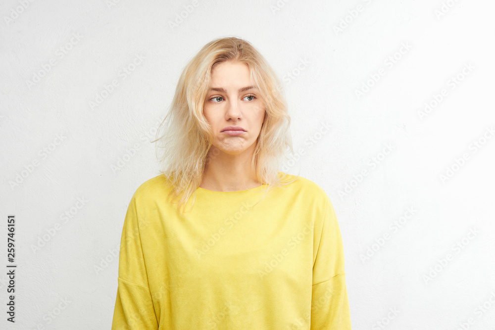 Portrait of beautiful upset European girl in yellow outfit isolated on white background. Distressed, disappointed face, offended woman Portrait of beautiful upset European girl in yellow outfit isolated on white background. Distressed, disappointed face, offended woman