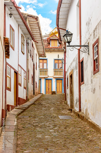 Facade of old houses built in colonial architecture with their balconies  roofs  colorful details and cobblestone street in the historical city of Ouro Preto in Minas Gerais.