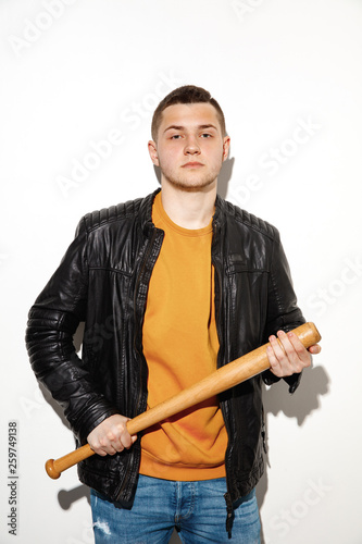 Sport games. Close up fashion portrait of young cool hipster boy wearing jeans wear. Man with a baseball bat.