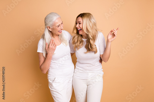 Portrait of nice-looking attractive lovely charming slim fit cheerful cheery ladies wearing white outfit laughing 1 april joke isolated over beige pastel background photo