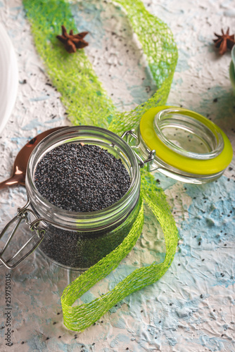 Glass jar with sealed cover full of raw poppy seeds on light board