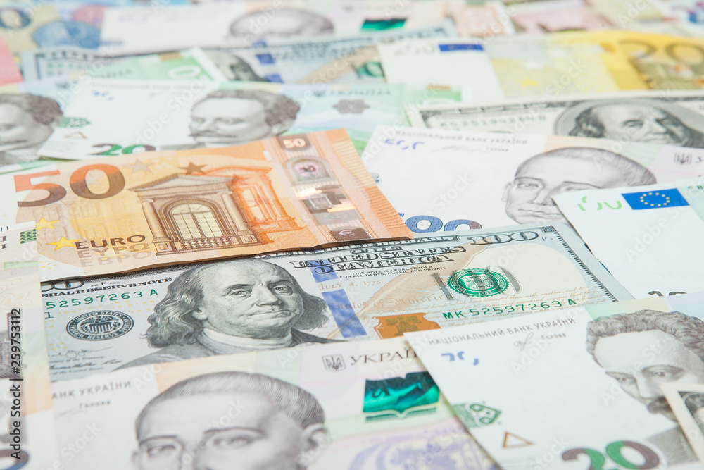 Money and finances concept. One hundred dollar new bill on colorful abstract background of Ukrainian, American and euro national currency banknotes Money and finances concept. One hundred dollar new bill on colorful abstract background of Ukrainian, American and euro national currency banknotes