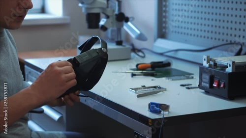 Worker puts on an antistatic belt on his right hand to avoid damage to the repaired device. Laboratory concept for the design and repair of mobile devices