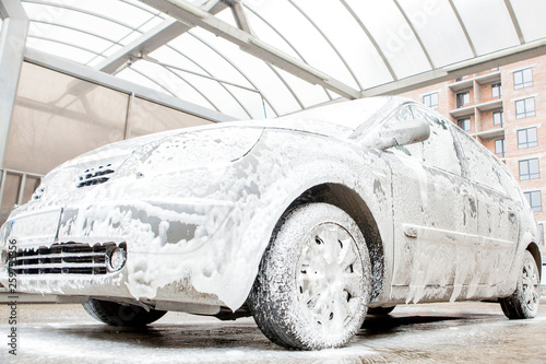 Car wash with foam in car wash station. Carwash. Washing machine at the station. Car washing concept. Car in foam photo
