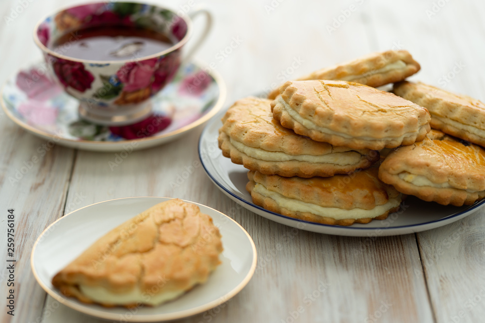Freshly baked sochni on white plates served with tea. White wooden background, high resolution