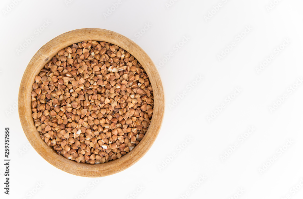 buckwheat groats in a wooden plate on a white background buckwheat groats in a wooden plate on a white background